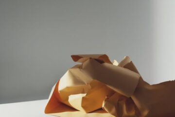 A crumpled yellow paper on a table casting shadows, in a minimalist style.