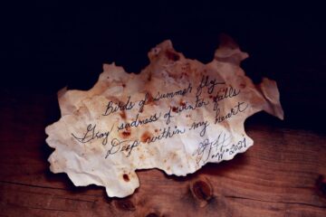A stained old paper with a handwritten poem creating a vintage and moody atmosphere.